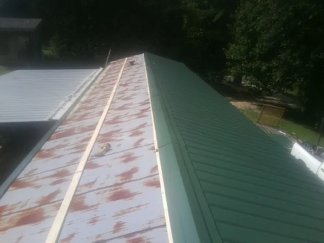 Old rusted panels beside newly installed green metal roofing — Wind Damage Roof Repair by Roofing Brothers in Usaf Academy