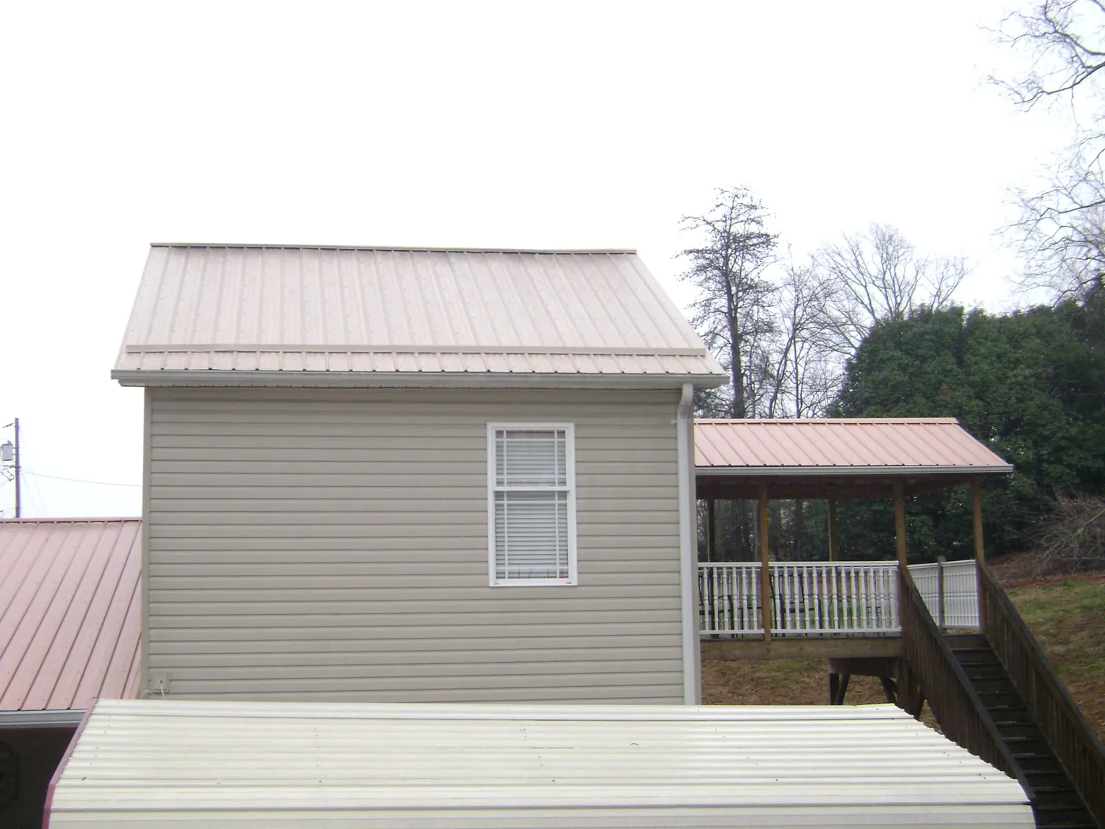Tan metal roofs on a two story addition and attached porch, from a Roof Replacement job in Usaf Academy