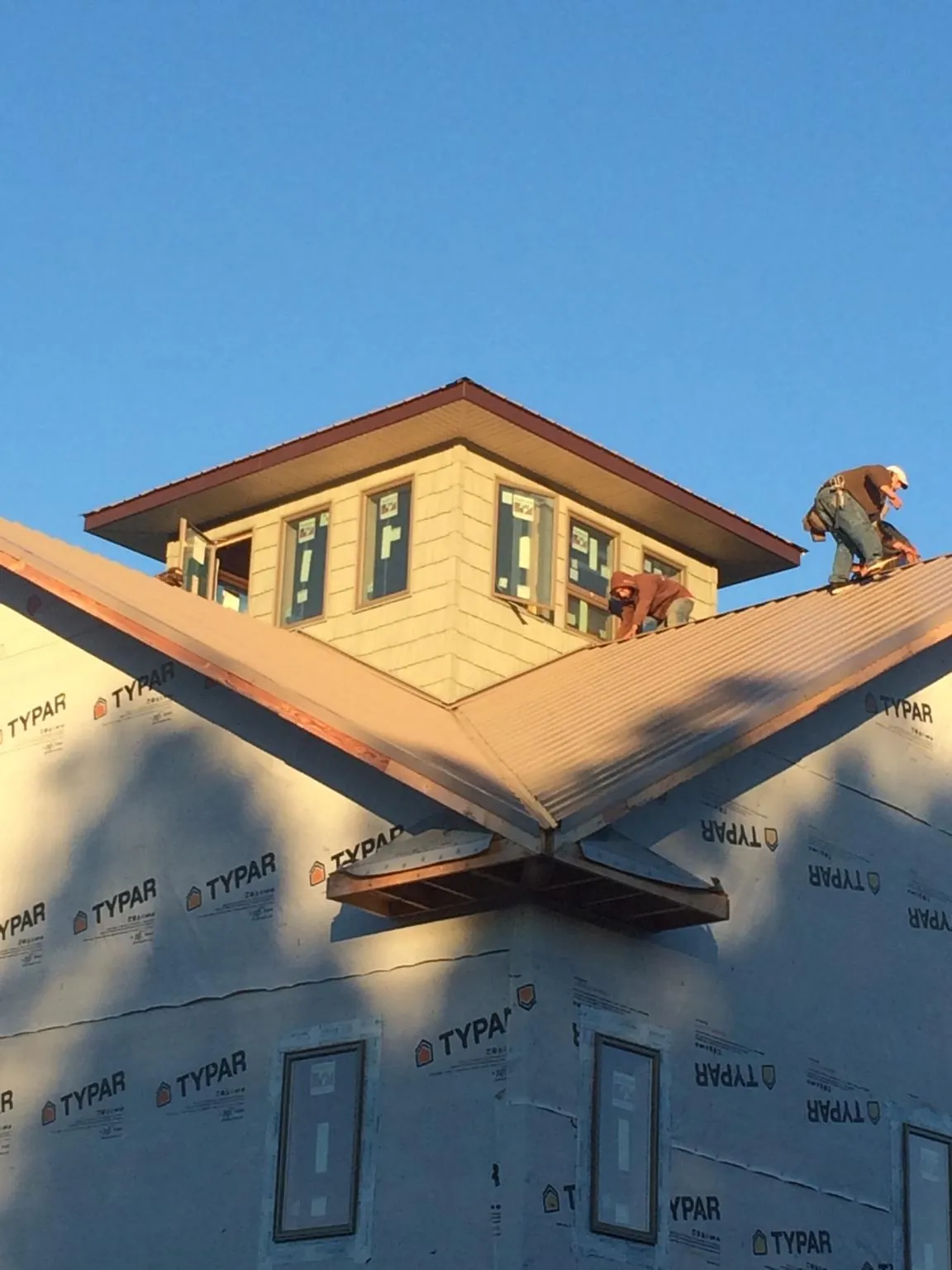 Roofers working around a rooftop cupola on a new metal roof at sunset — Roof Waterproofing in Usaf Academy by Roofing Brothers